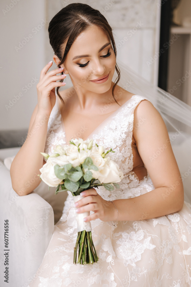 Naklejka premium Gorgeous bride close her eyes and show beautiful make-up. Woman hold elegant wedding bouquet in hands and sits on chair.