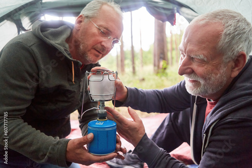 Senior man fixing burner on stove with friend