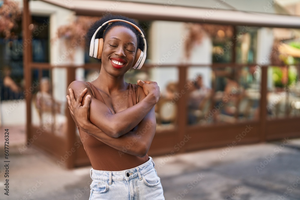 African woman with curly hair outdoors at the city wearing headphones winking looking at the camera with sexy expression, cheerful and happy face. African woman with curly hair outdoors at the city wearing headphones winking looking at the camera with sexy expression, cheerful and happy face.