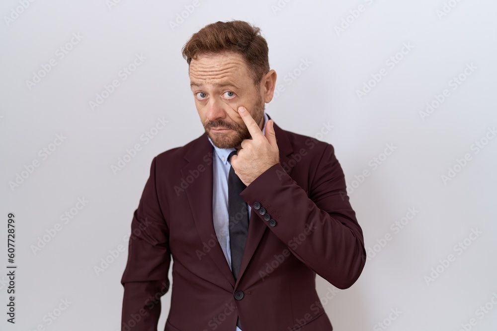 Middle age business man with beard wearing suit and tie pointing to the eye watching you gesture, suspicious expression Middle age business man with beard wearing suit and tie pointing to the eye watching you gesture, suspicious expression