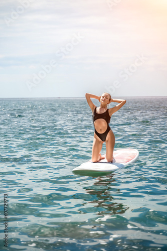Woman sup sea. Sports girl on a surfboard in the sea on a sunny summer day. In a black bathing suit, he sits on a sapa in the sea. Rest on the sea.