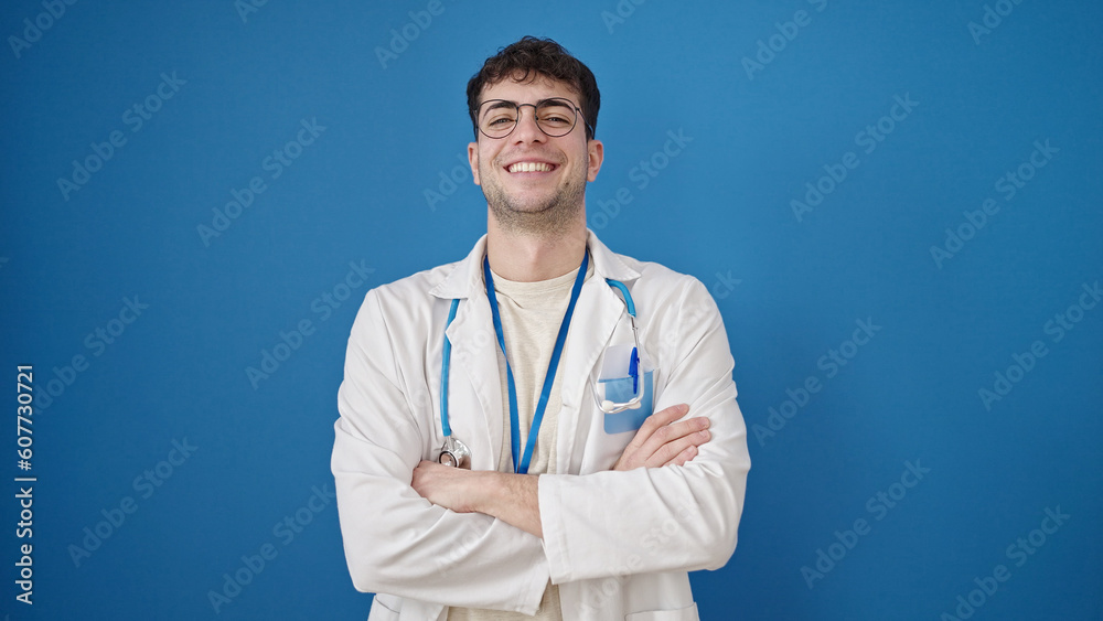 Young hispanic man doctor smiling confident standing with arms crossed gesture over isolated blue background Young hispanic man doctor smiling confident standing with arms crossed gesture over isolated blue background