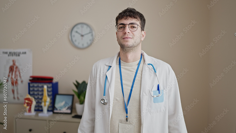 Young hispanic man doctor standing with serious expression at clinic Young hispanic man doctor standing with serious expression at clinic