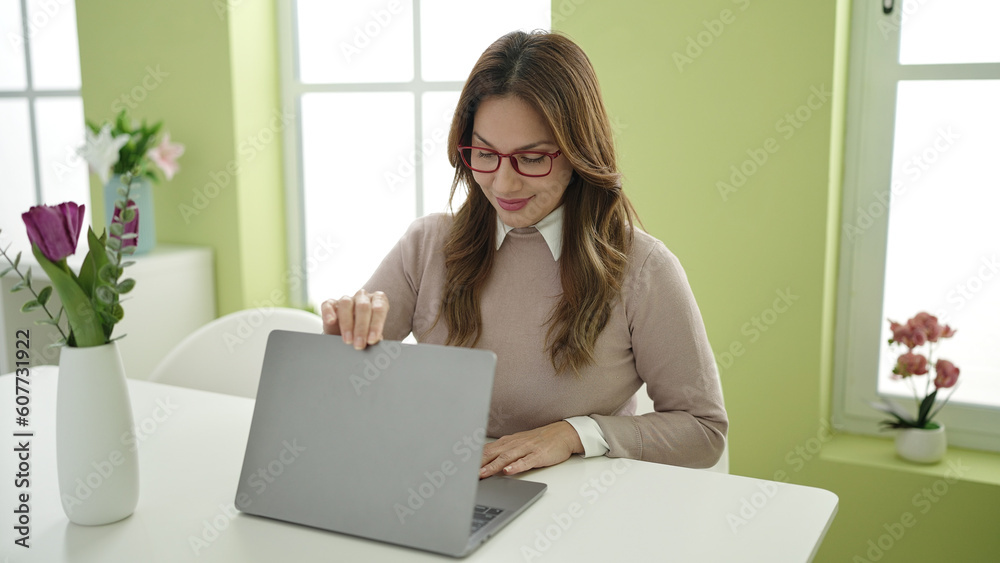 Young beautiful hispanic woman using laptop sitting on table at home Young beautiful hispanic woman using laptop sitting on table at home