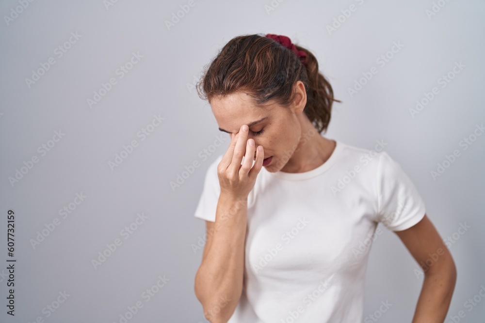 Beautiful brunette woman standing over isolated background tired rubbing nose and eyes feeling fatigue and headache. stress and frustration concept. Beautiful brunette woman standing over isolated background tired rubbing nose and eyes feeling fatigue and headache. stress and frustration concept.