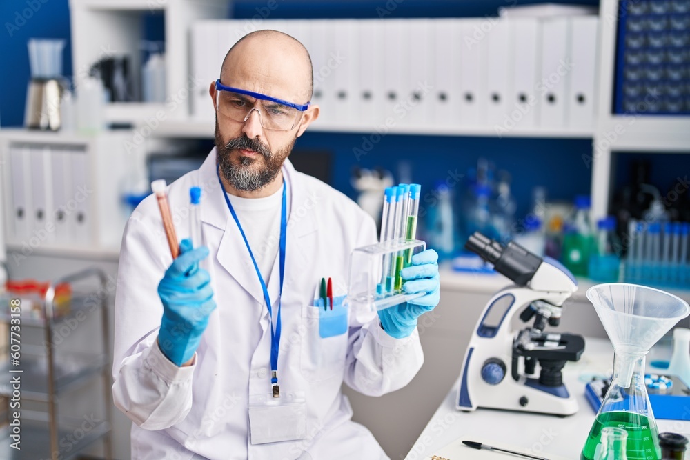 Young bald man scientist holding test tubes at laboratory Young bald man scientist holding test tubes at laboratory