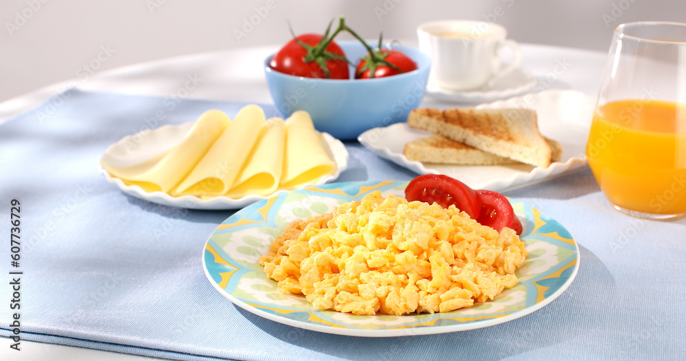 scrambled eggs and tomato on blue table. breakfast on a plate. food on a sunny morning. fried eggs close-up.