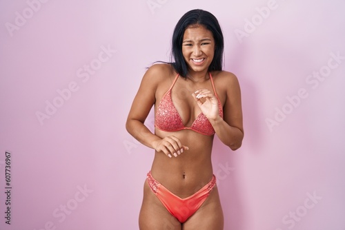 Hispanic woman wearing bikini disgusted expression, displeased and fearful doing disgust face because aversion reaction.