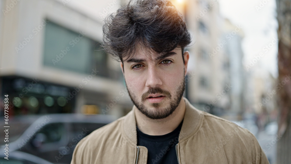 Naklejka premium Young hispanic man standing with serious expression at street