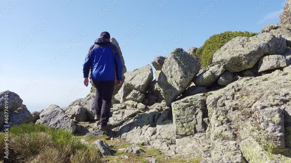 Man with his back climbing a rocky mountain along a path between the large stones, Madrid, Guadarrama. Man with his back climbing a rocky mountain along a path between the large stones, Madrid, Guadarrama.