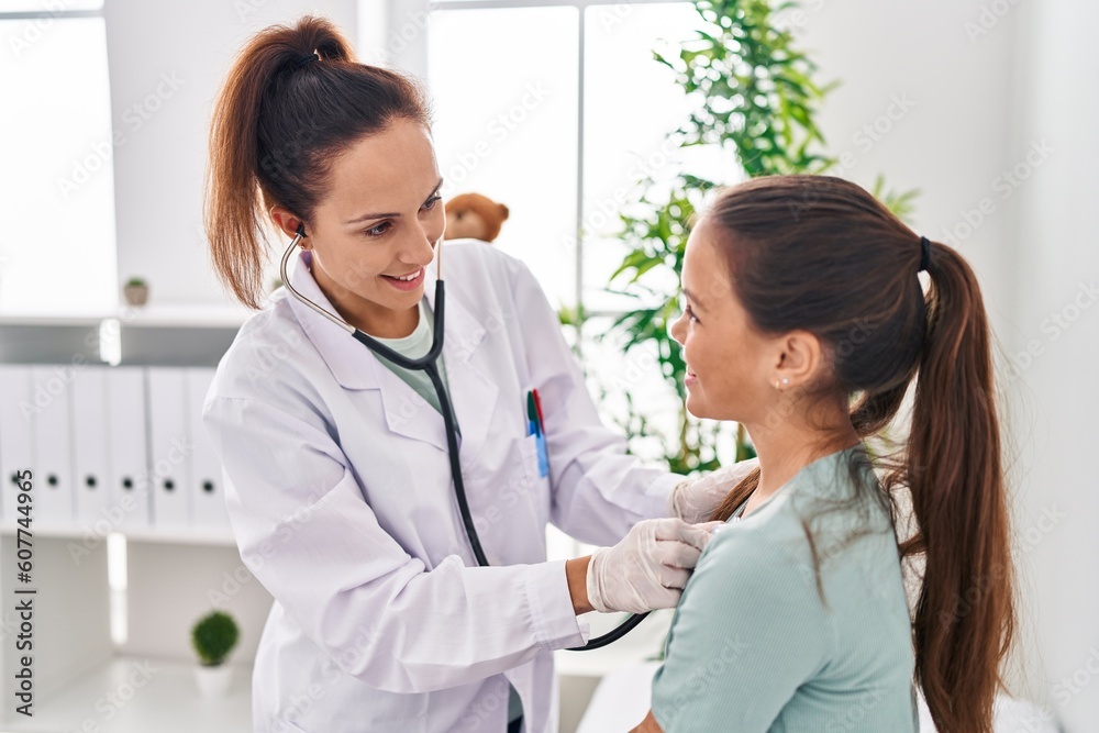 Woman and girl doctor and patient auscultating chest at clinic