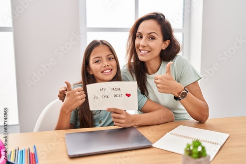 Young mother and daughter holding my mom is the best smiling happy and positive, thumb up doing excellent and approval sign