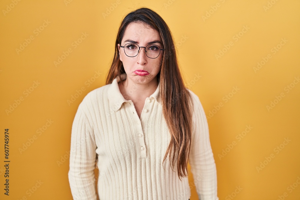 Young hispanic woman standing over yellow background depressed and worry for distress, crying angry and afraid. sad expression.