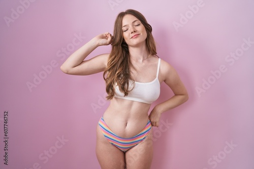 Caucasian woman wearing lingerie over pink background stretching back, tired and relaxed, sleepy and yawning for early morning