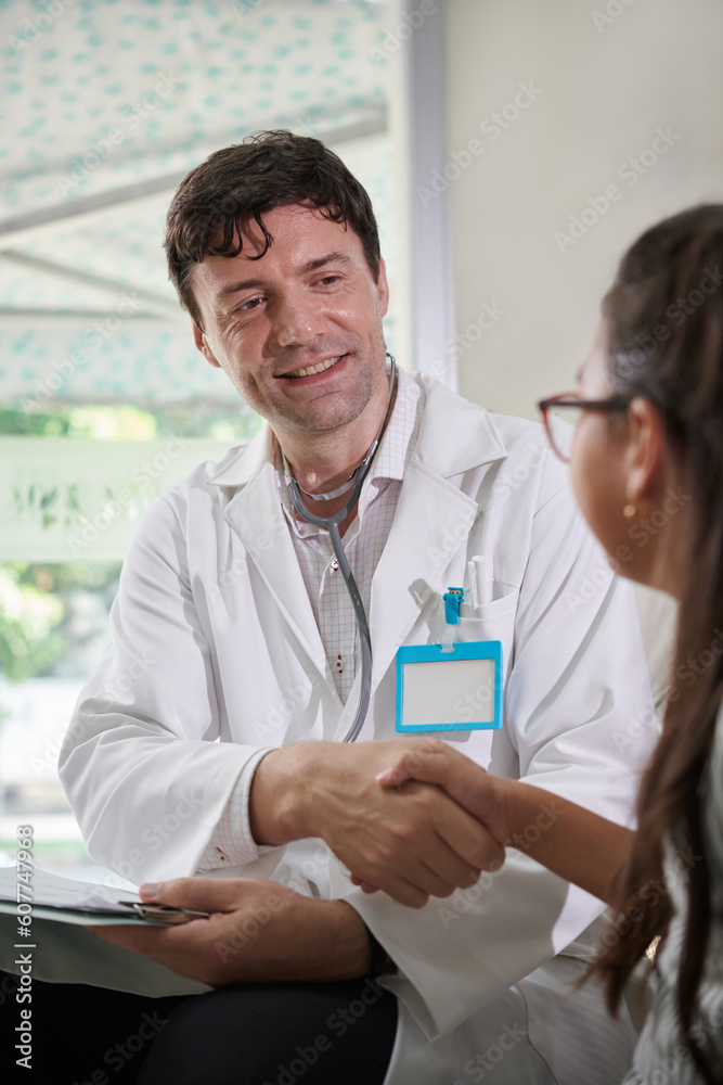 Smiling pediatrician shaking hand of little patient Smiling pediatrician shaking hand of little patient