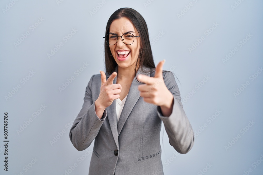 Hispanic business woman wearing glasses pointing fingers to camera with happy and funny face. good energy and vibes. Hispanic business woman wearing glasses pointing fingers to camera with happy and funny face. good energy and vibes.