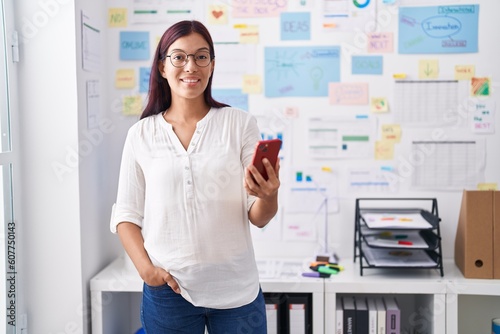 Young beautiful hispanic woman business worker smiling confident using smartphone at office