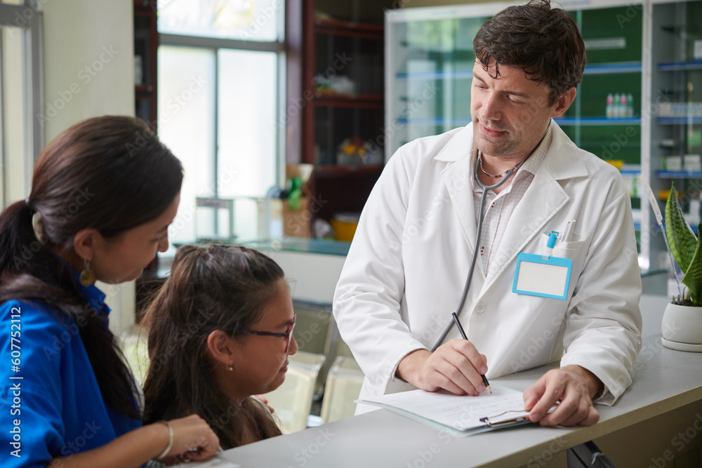 Pediatrician filling medical card when talking to preteen girl Pediatrician filling medical card when talking to preteen girl