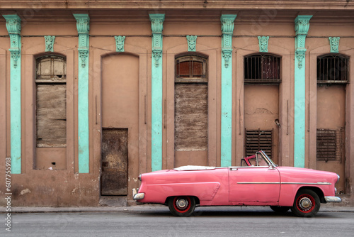 Canvas Print A side photo of a pink car in Havana, Cuba park in front of an brown facade