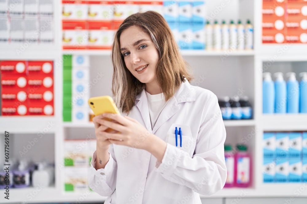 Young woman pharmacist using smartphone at pharmacy