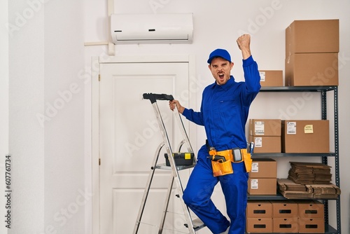 Young hispanic man working at renovation annoyed and frustrated shouting with anger, yelling crazy with anger and hand raised