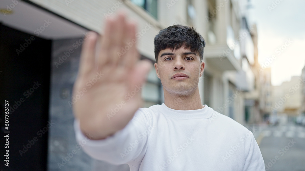 Young hispanic man doing stop gesture with hand at street Young hispanic man doing stop gesture with hand at street