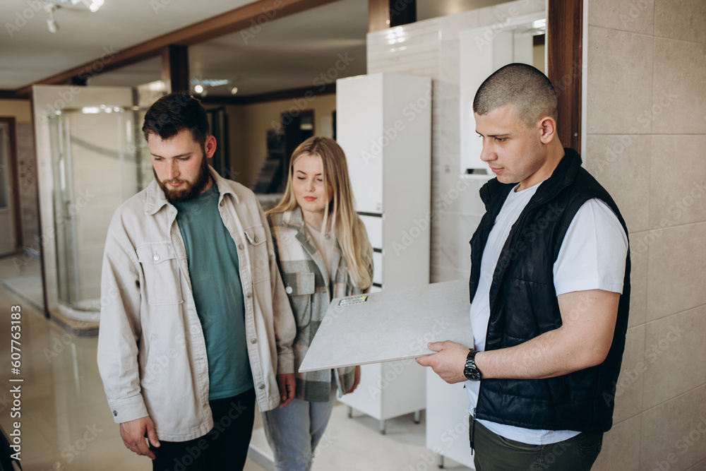 Positive couple choosing kitchen ceramic tile in modern shop. Positive couple choosing kitchen ceramic tile in modern shop.