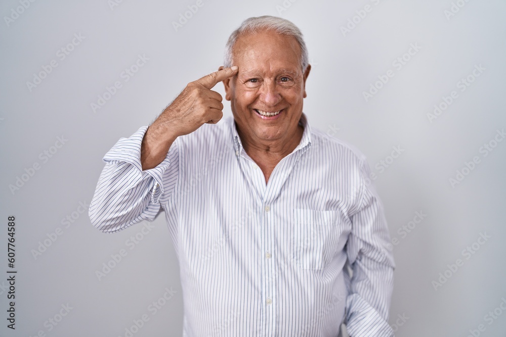 Senior man with grey hair standing over isolated background smiling pointing to head with one finger, great idea or thought, good memory Senior man with grey hair standing over isolated background smiling pointing to head with one finger, great idea or thought, good memory