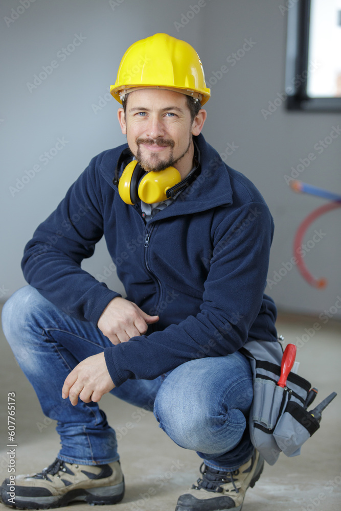 young friendly tradesman crouching to the floor