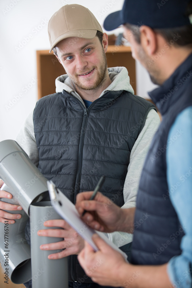 happy blue-collar with coworker holding plastic pipes happy blue-collar with coworker holding plastic pipes