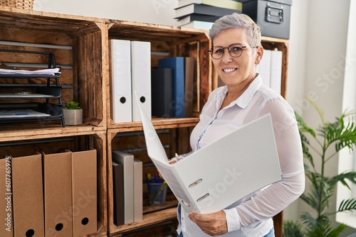 Middle age woman psychologist reading binder standing at pyschology center photo