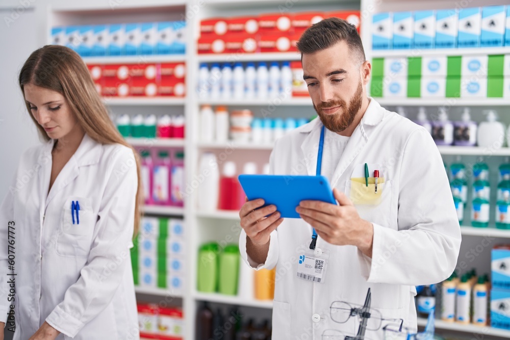 Man and woman pharmacists using touchpad working at pharmacy