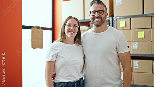 Young woman and man working on ecommerce standing looking at the camera at office