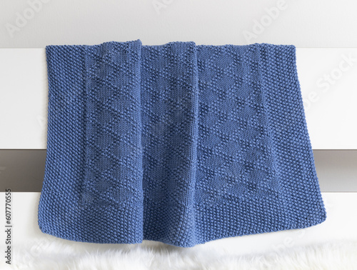 Navy blue knitted blanket in brocade knitting pattern on a white background