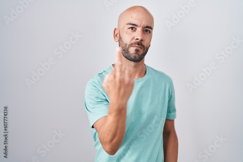 Middle age bald man standing over white background showing middle finger, impolite and rude fuck off expression