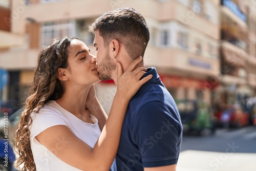 Young hispanic couple smiling confident hugging each other and kissing at street