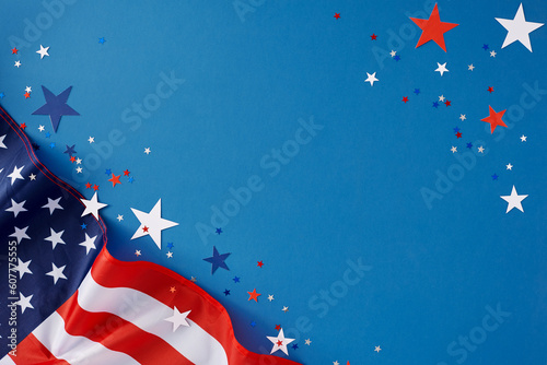 July 4th celebration theme concept. Top view flat lay of american flag and patriotic star-shaped confetti on blue background with blank space for text or advert