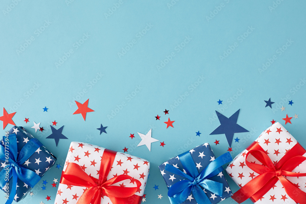 Fourth of July festivities concept. Top view flat lay of gift boxes in patriotic colors, star-shaped confetti on pastel blue background with empty space for text or greeting Fourth of July festivities concept. Top view flat lay of gift boxes in patriotic colors, star-shaped confetti on pastel blue background with empty space for text or greeting