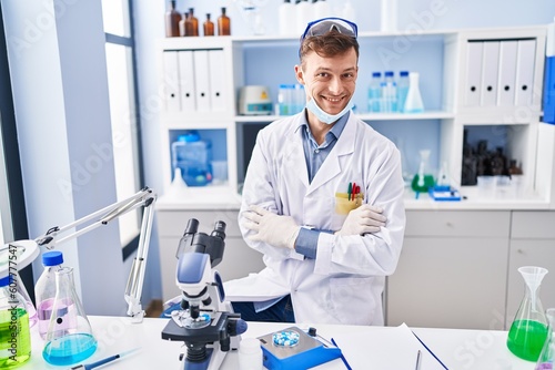 Caucasian man working at scientist laboratory happy face smiling with crossed arms looking at the camera. positive person.