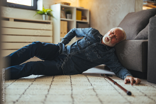 A Senior Man who is Using a Walking Stick is Lying on the Wooden Floor in his Apartment After he Fell in Serious Accident. Senior man lying on the floor of his room in an assisted living home © Dragana Gordic