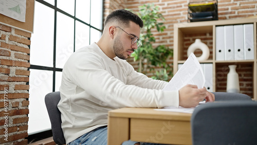 Young hispanic man business worker reading document at office