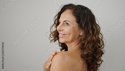 Middle age hispanic woman smiling confident applying skin treatment over isolated white background