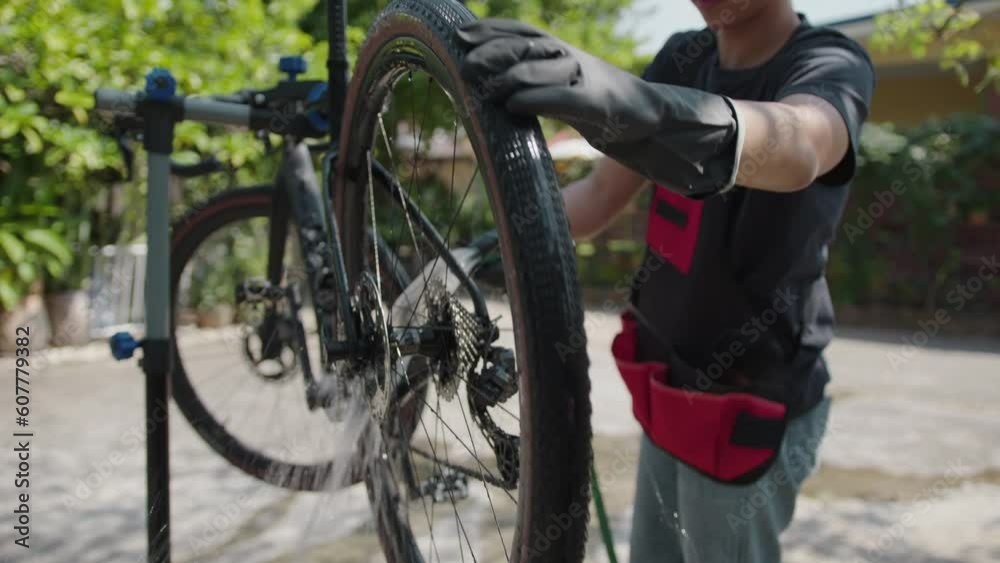 Asian bike mechanic washing a customer's bike. Asian bike mechanic washing a customer's bike.