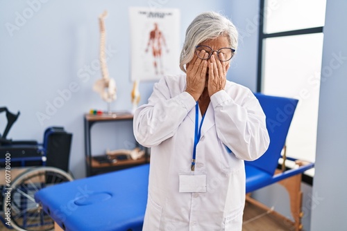 Middle age woman with grey hair working at pain recovery clinic rubbing eyes for fatigue and headache  sleepy and tired expression. vision problem