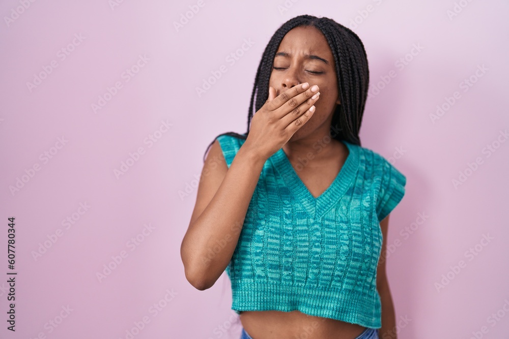 Young african american with braids standing over pink background bored yawning tired covering mouth with hand. restless and sleepiness. Young african american with braids standing over pink background bored yawning tired covering mouth with hand. restless and sleepiness.