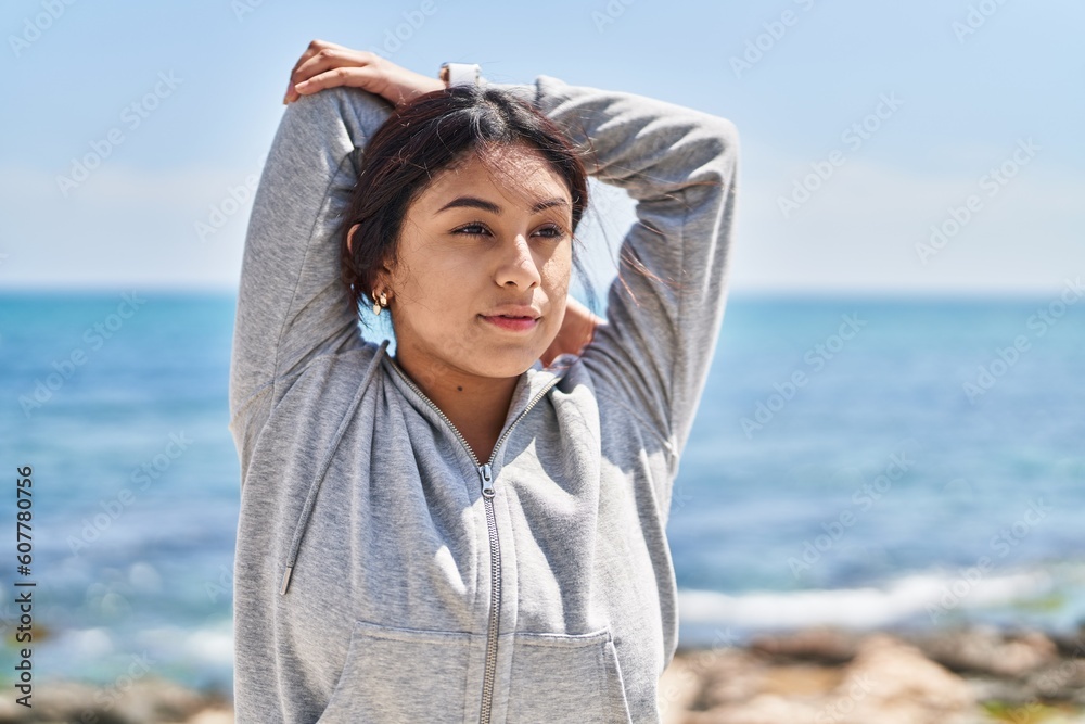 Young hispanic woman stretching arms training at seaside Young hispanic woman stretching arms training at seaside