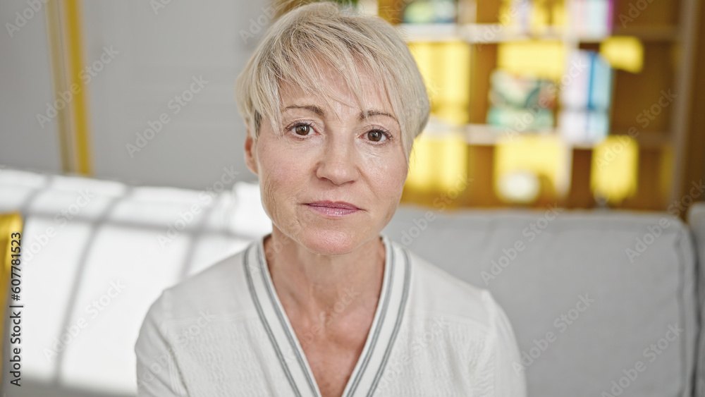 Middle age blonde woman sitting on sofa with relaxed expression at home Middle age blonde woman sitting on sofa with relaxed expression at home