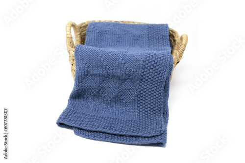 Navy blue wool knitted blanket in harlequin knitting pattern in a basket on a white background