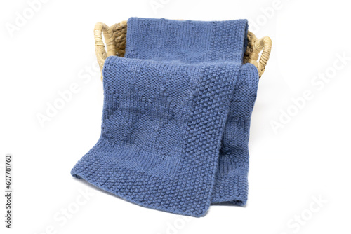 Navy blue wool knitted blanket in harlequin knitting pattern in a basket on a white background