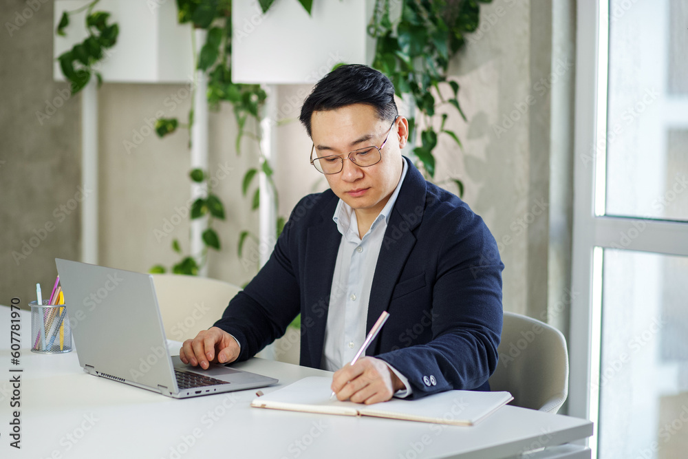 Asian businessman working in office, using laptop. Human resources. Finance concept. Multiracial Asian businessman working in office, using laptop. Human resources. Finance concept. Multiracial